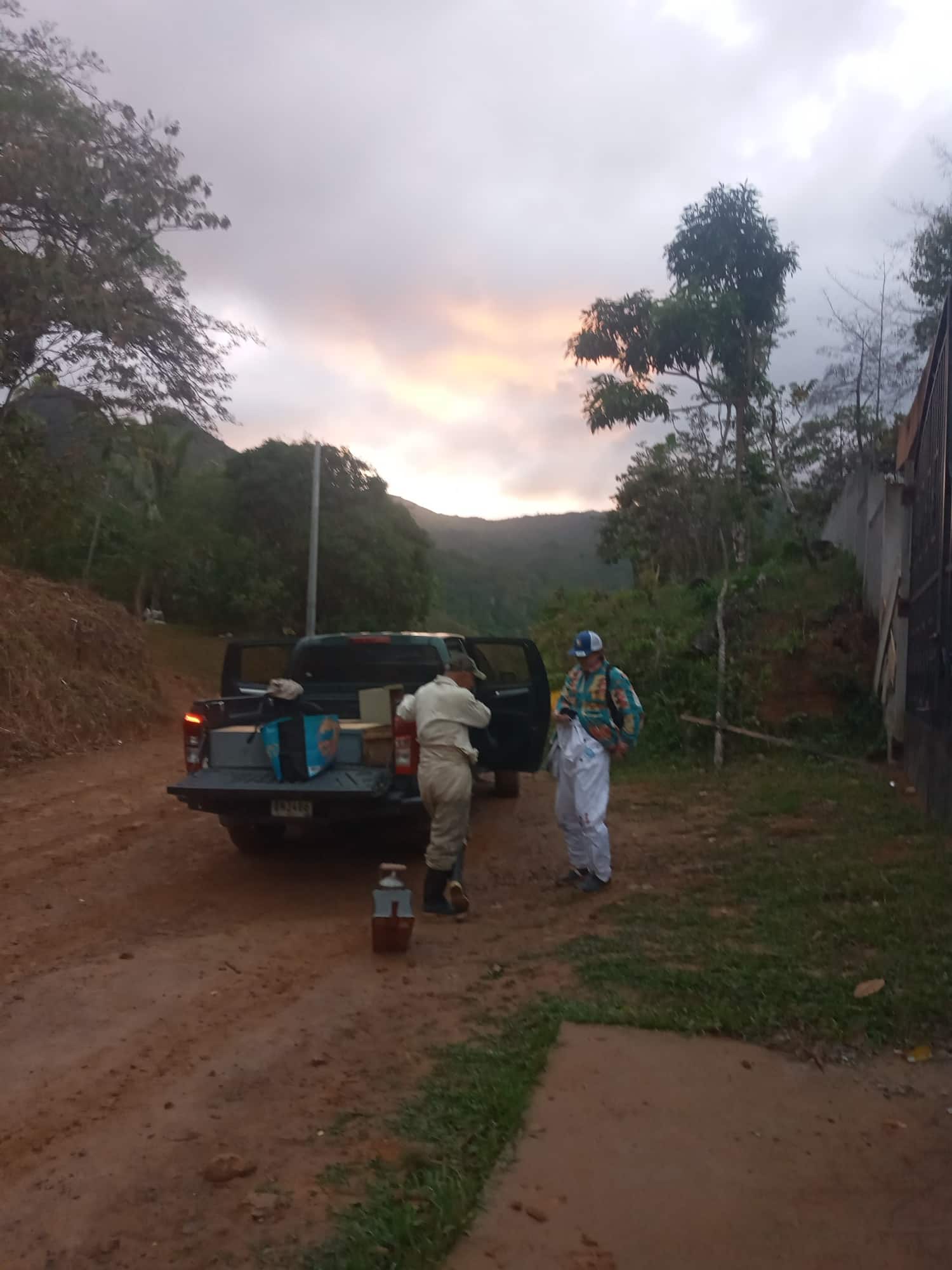 Al amanecer, dos apicultores descargan el equipo de la camioneta en el camino de tierra, Santa Fe de Veraguas