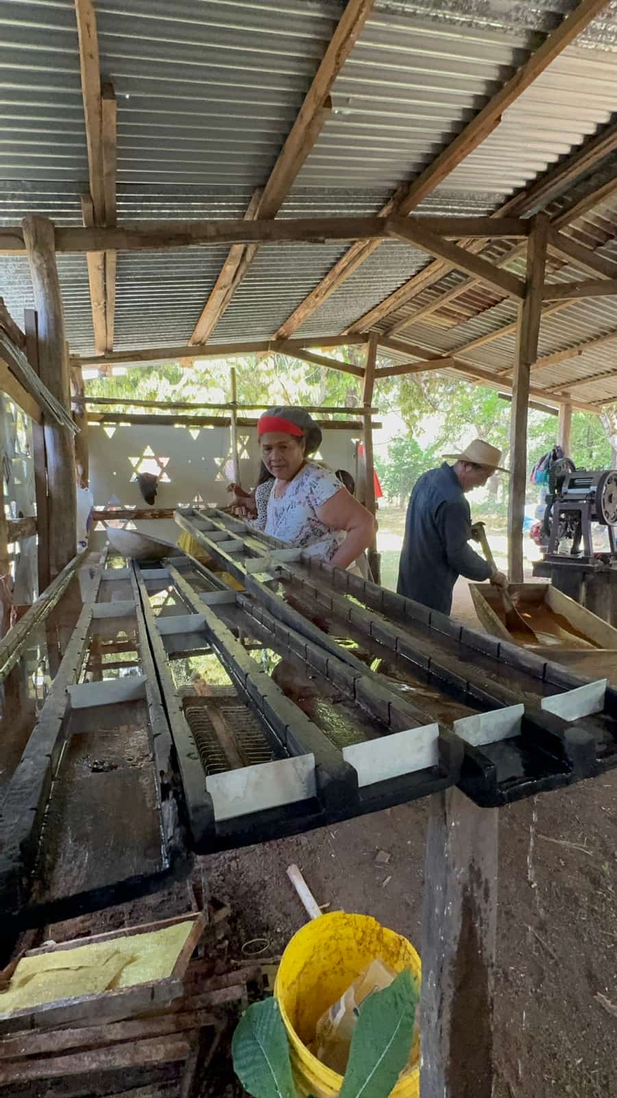 Hombres trabajando las canoas de jugo de caña bajo el techo del trapiche, San Juan de Veraguas